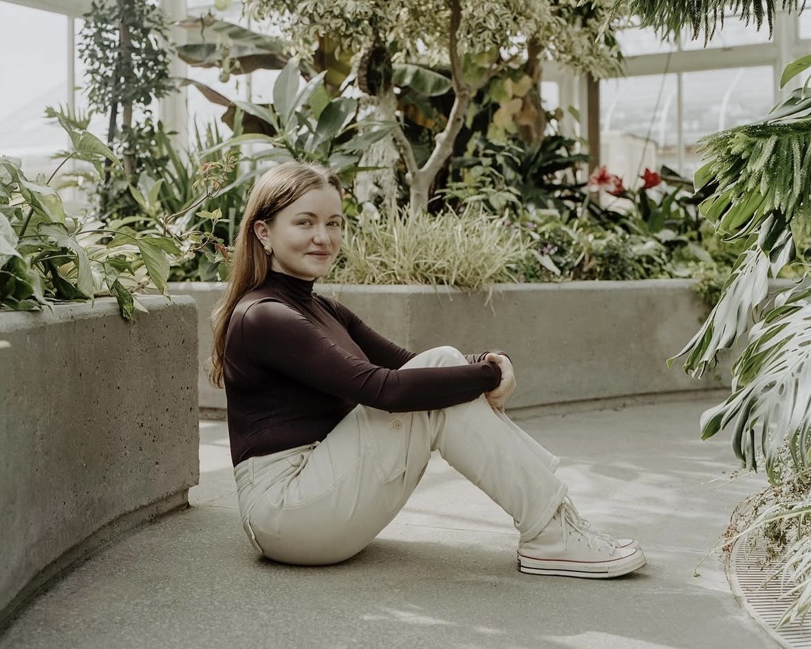 AP sitting in a greenhouse surrounded by plants